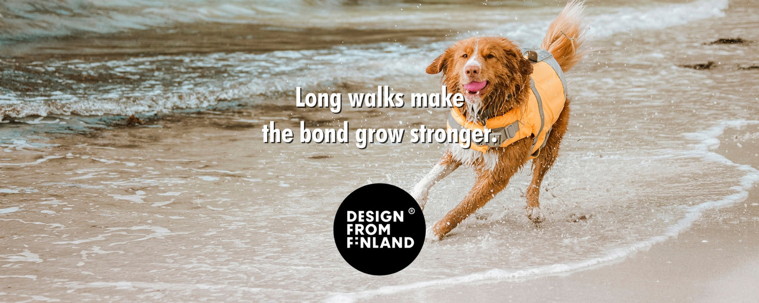 A golden retriever running through shallow ocean water on a beach, wearing a yellow hurtta vest. White text reads 'Long walks make the bond grow stronger.
